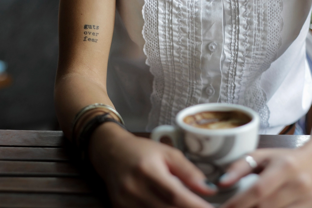 woman “guts fear” tattoo sitting