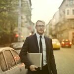 determined smiling businessman with laptop on street